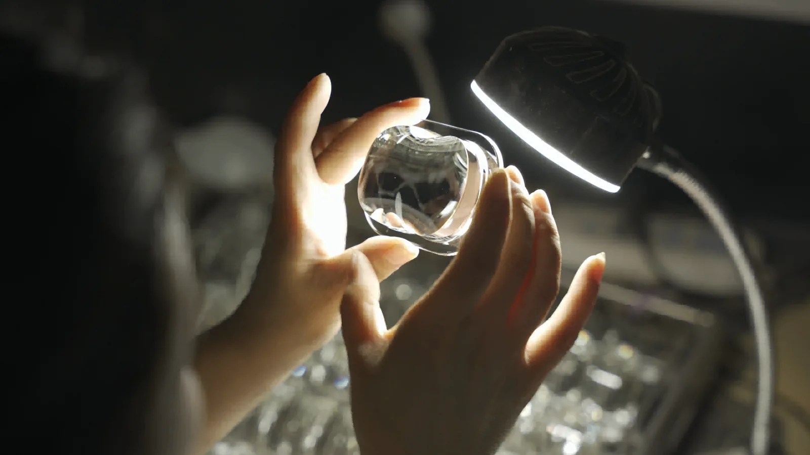 BO-Glass inspector examining a molded glass optic under an inspection lamp