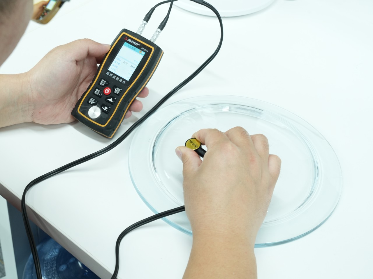 BO-Glass worker using an ultrasonic thickness gauge on a glass component