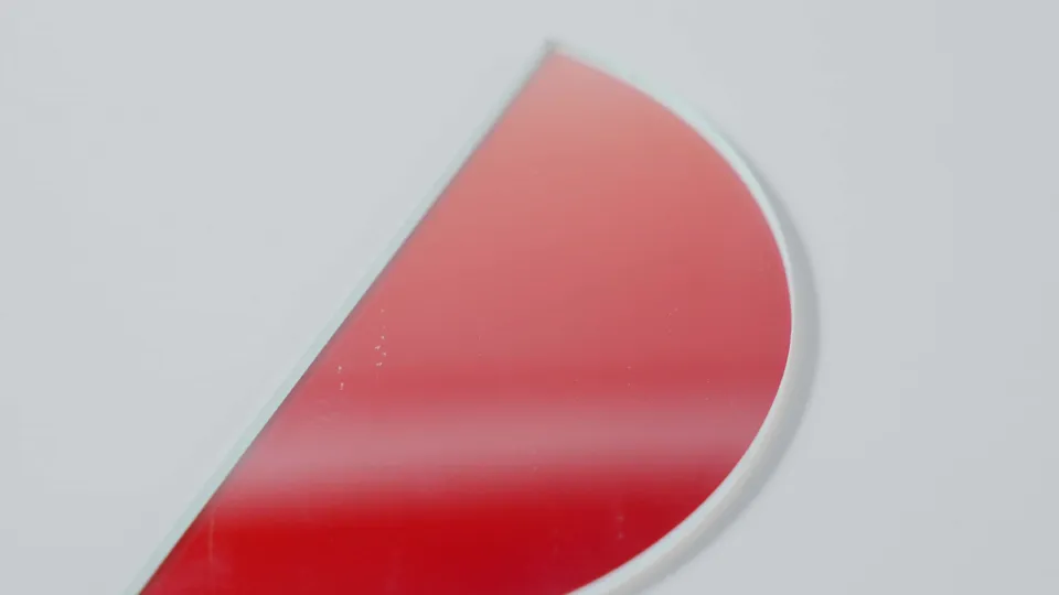 Red-coated optical filter glass photographed on a neutral background