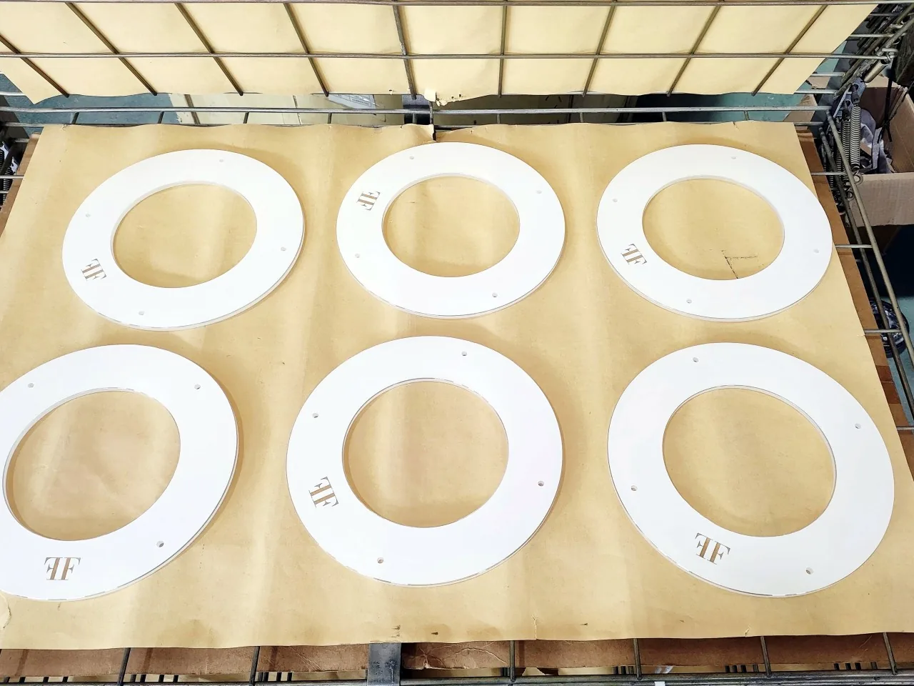 White printed ring-shaped glass components arranged as a production batch.