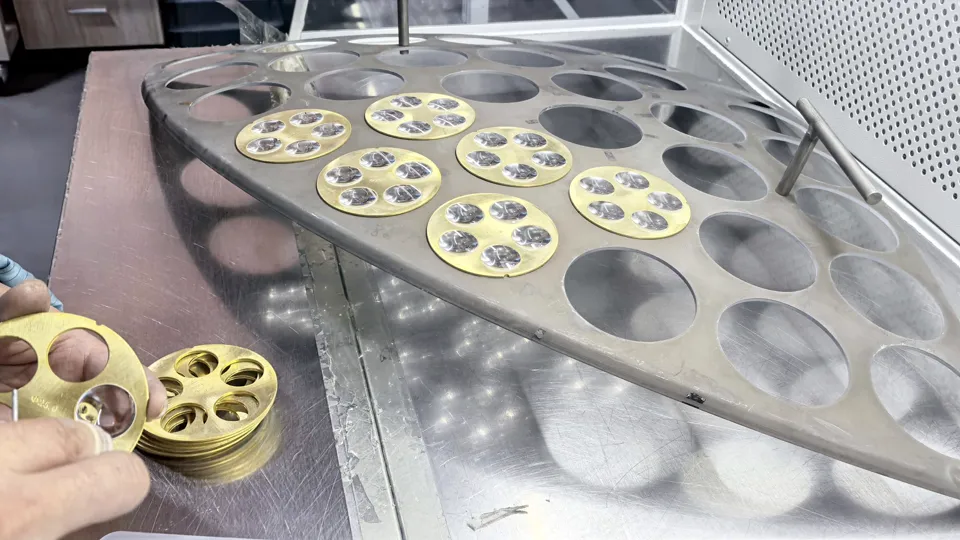 Small optical glass parts being loaded into reusable coating fixtures