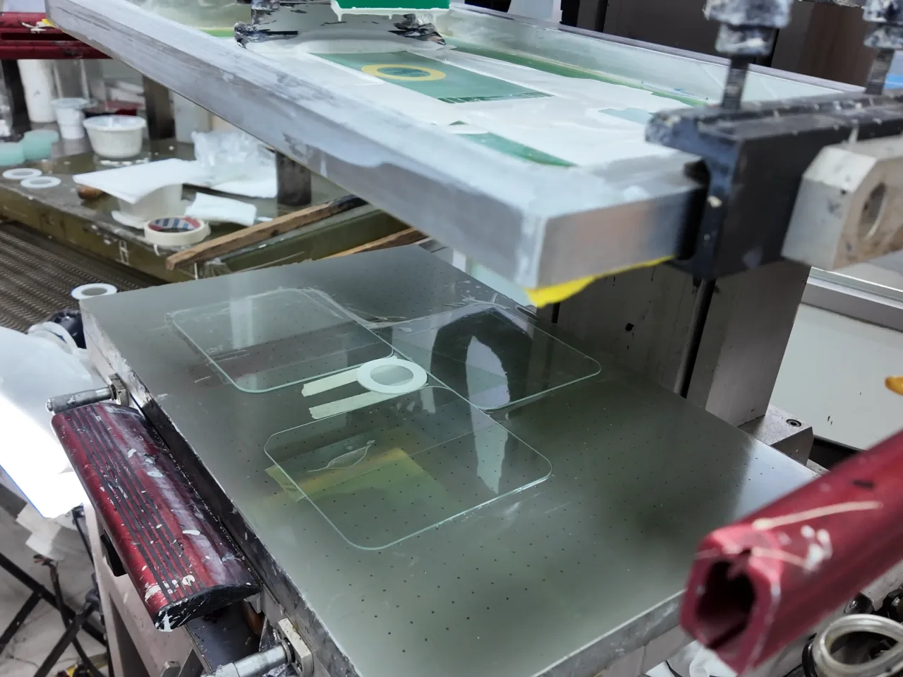 Production screen raised above multiple glass components on a supported print bed.