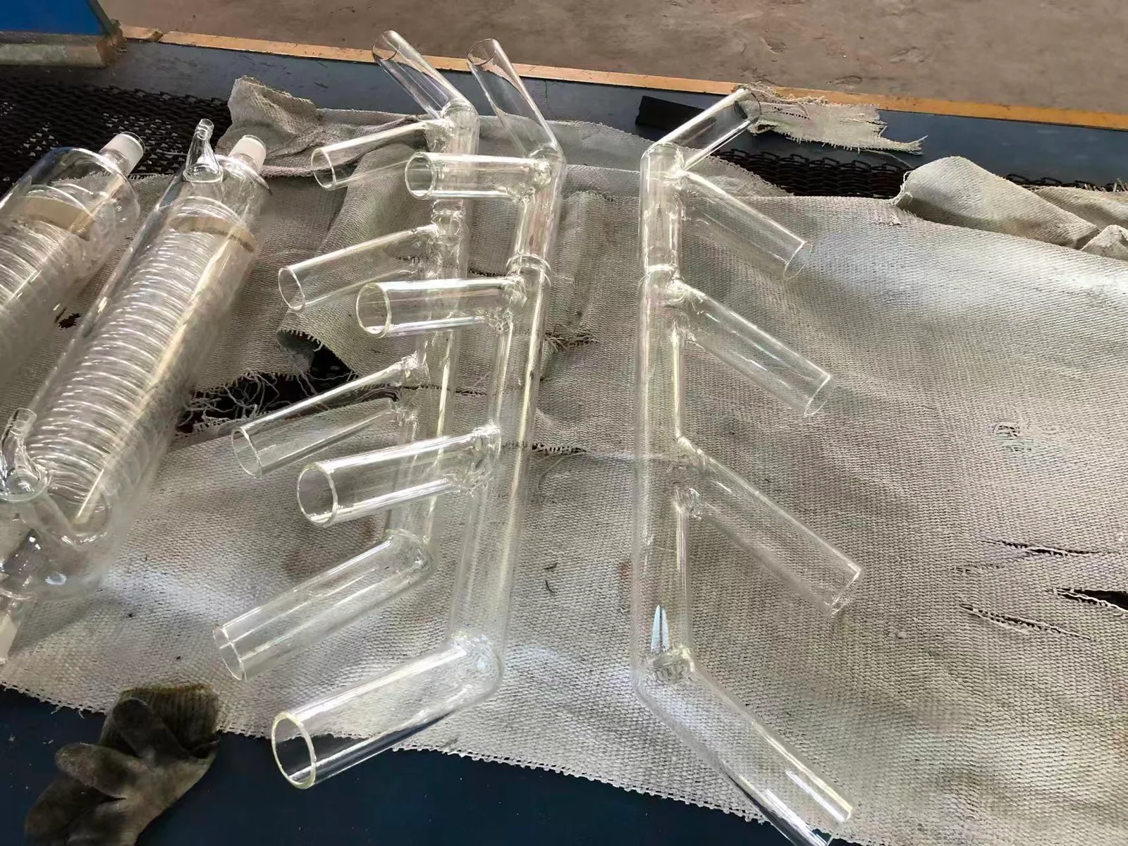 Clear glass tube assemblies with multiple side branches resting on fabric.
