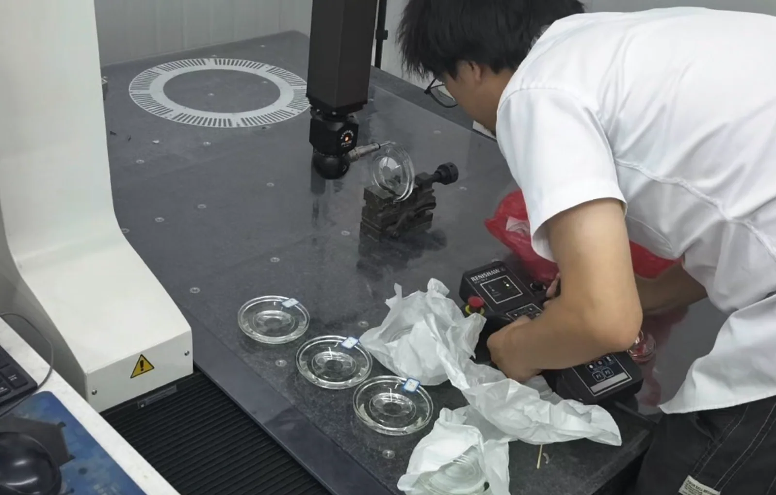Operator setting up a clear circular glass component in a coordinate measurement fixture