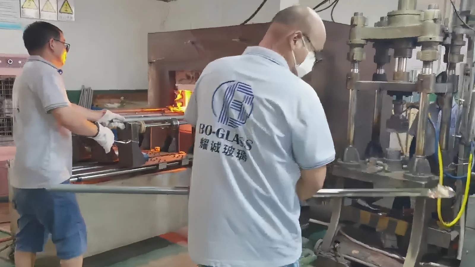 Operators working at glass pressing equipment in the workshop