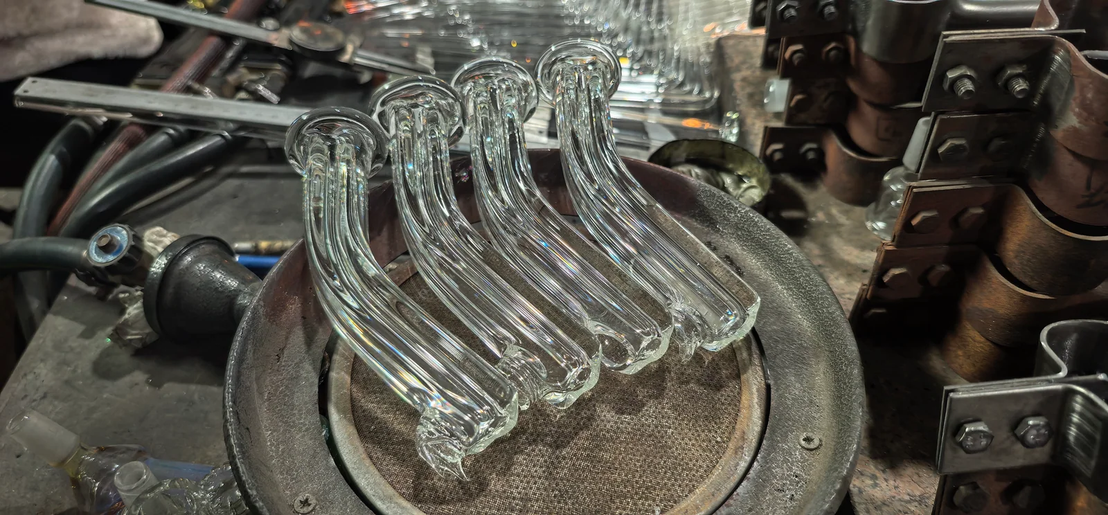 Clear glass tubes with bends and flared ends arranged on a workbench.