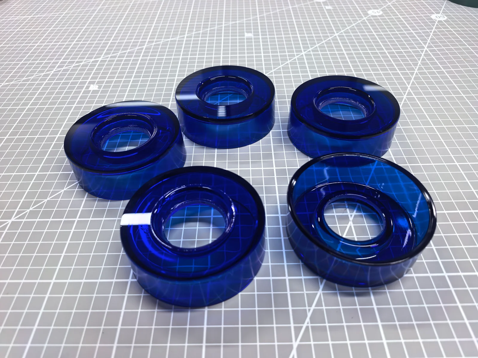 Blue glass ring components arranged on a gridded work surface