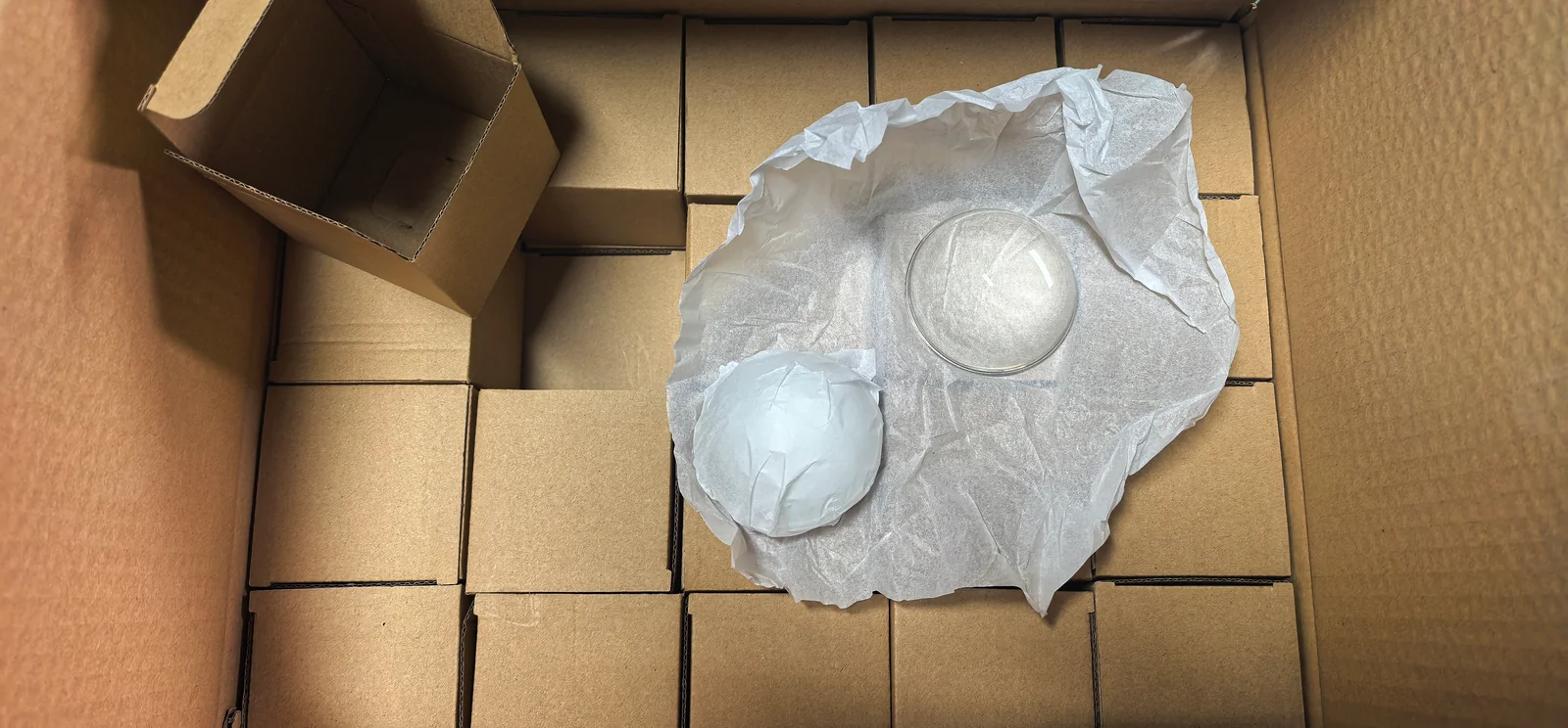 A clear glass component with protective wrapping and individual cardboard boxes