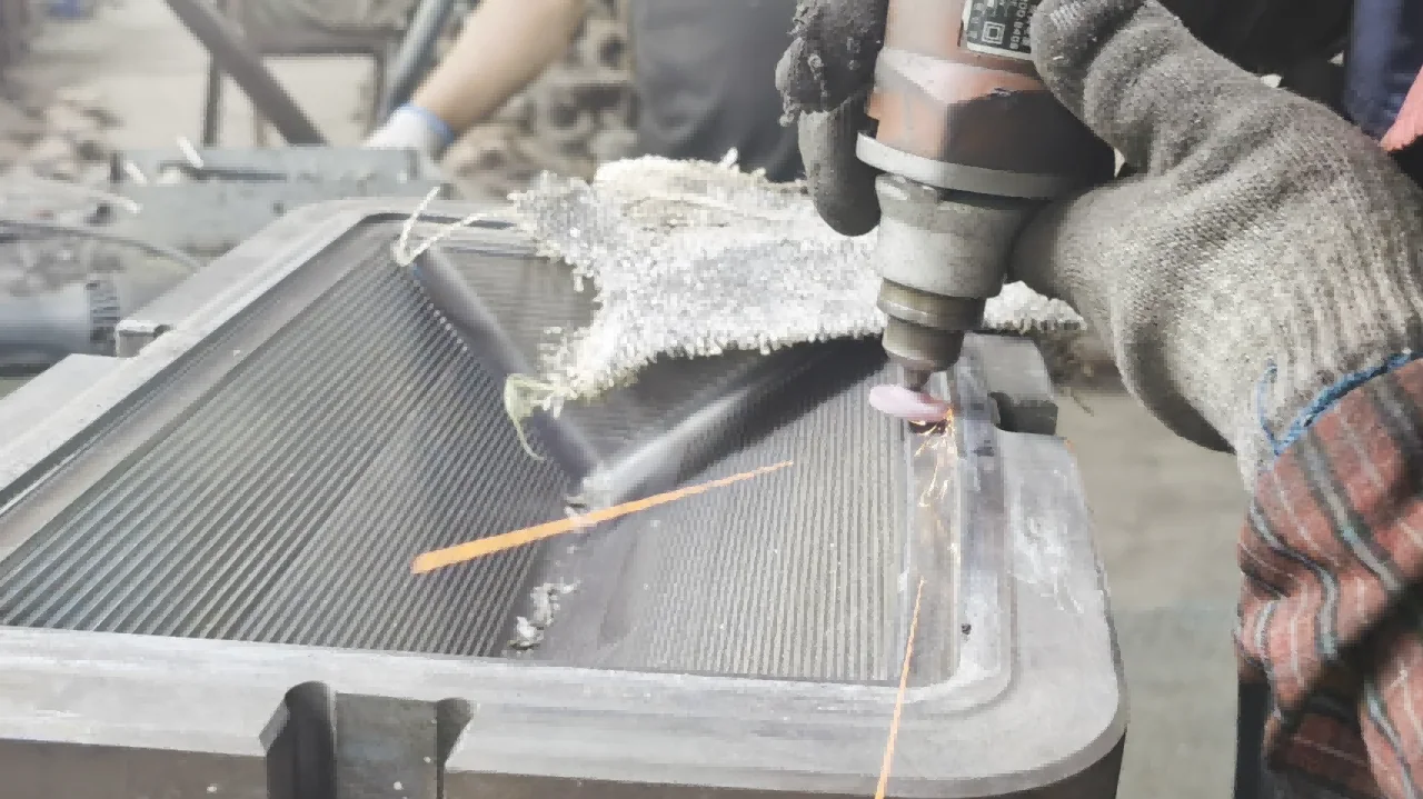 A gloved operator using a small rotary tool on the edge of a patterned rectangular glass mould