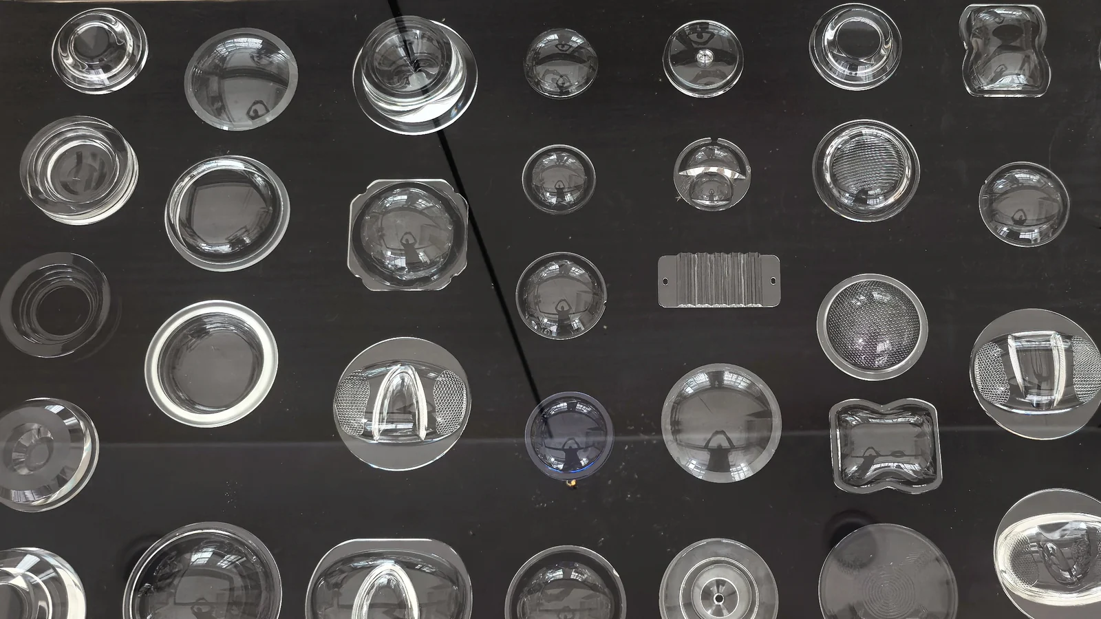 Assortment of clear circular, rectangular and textured glass components on a dark display surface