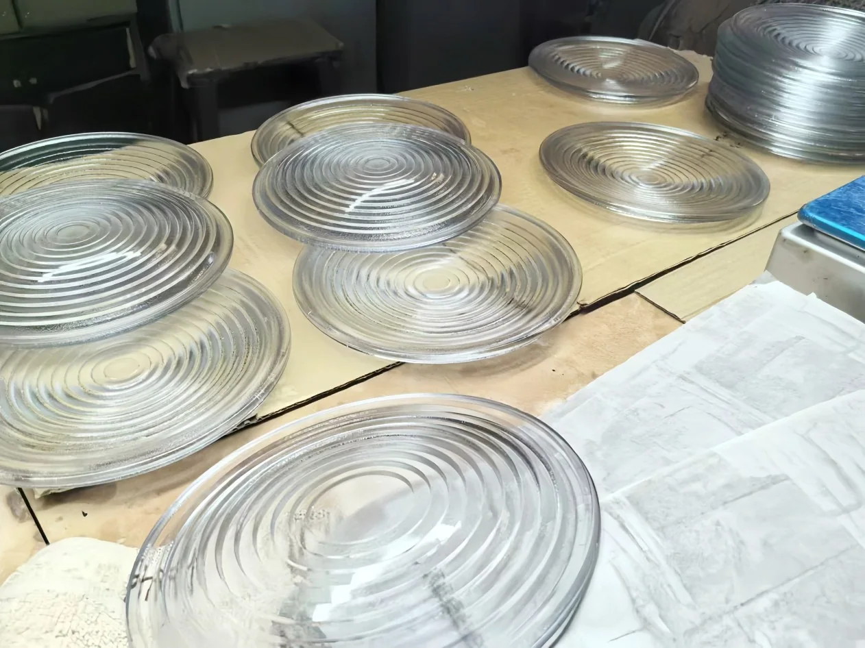 Clear round glass covers with concentric ribs arranged on a workshop surface