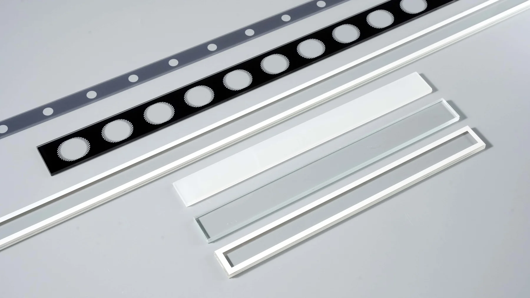 Real black and white printed glass strips with repeated apertures and perimeter borders.
