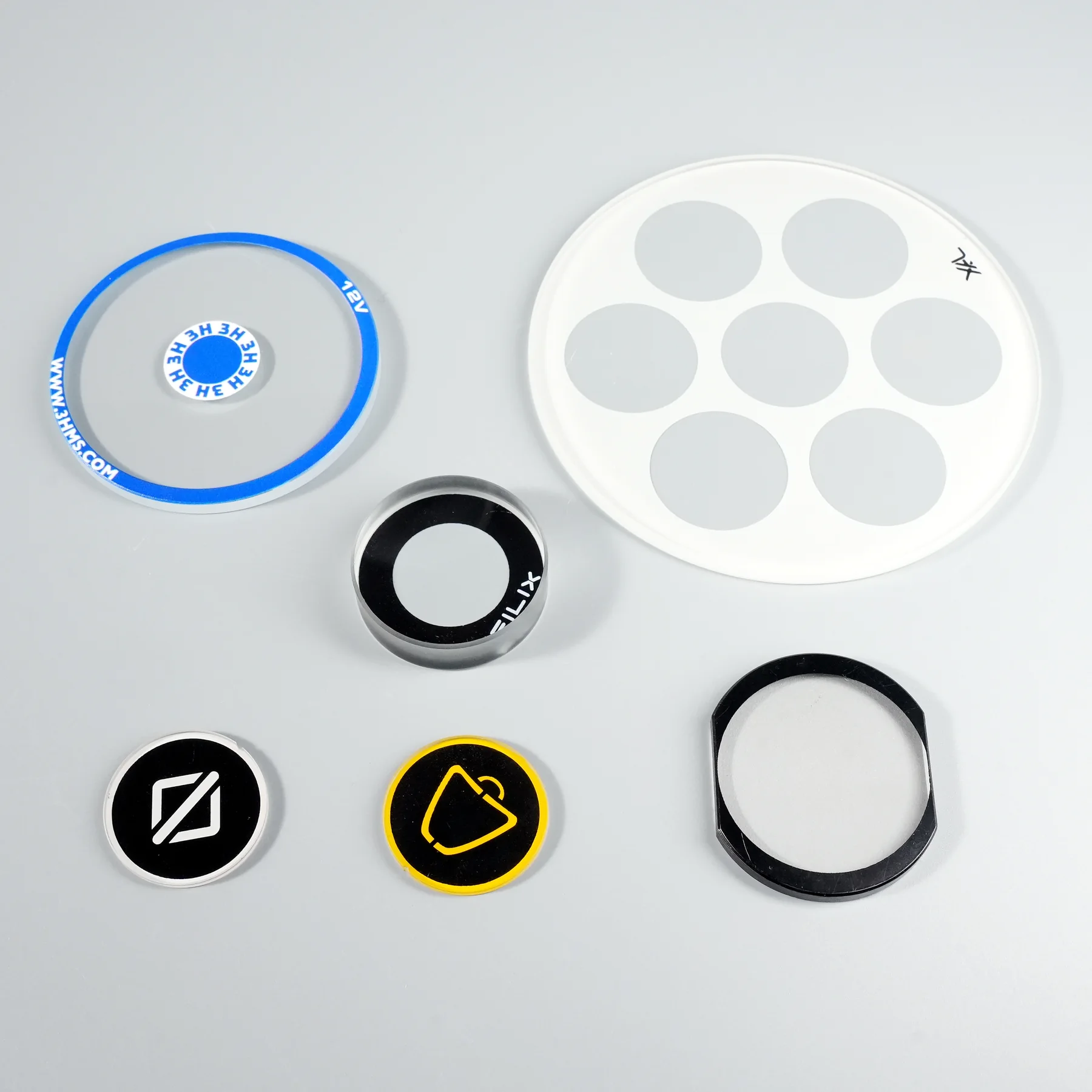 Real circular and irregular glass samples with black, white and multicolor printed areas.