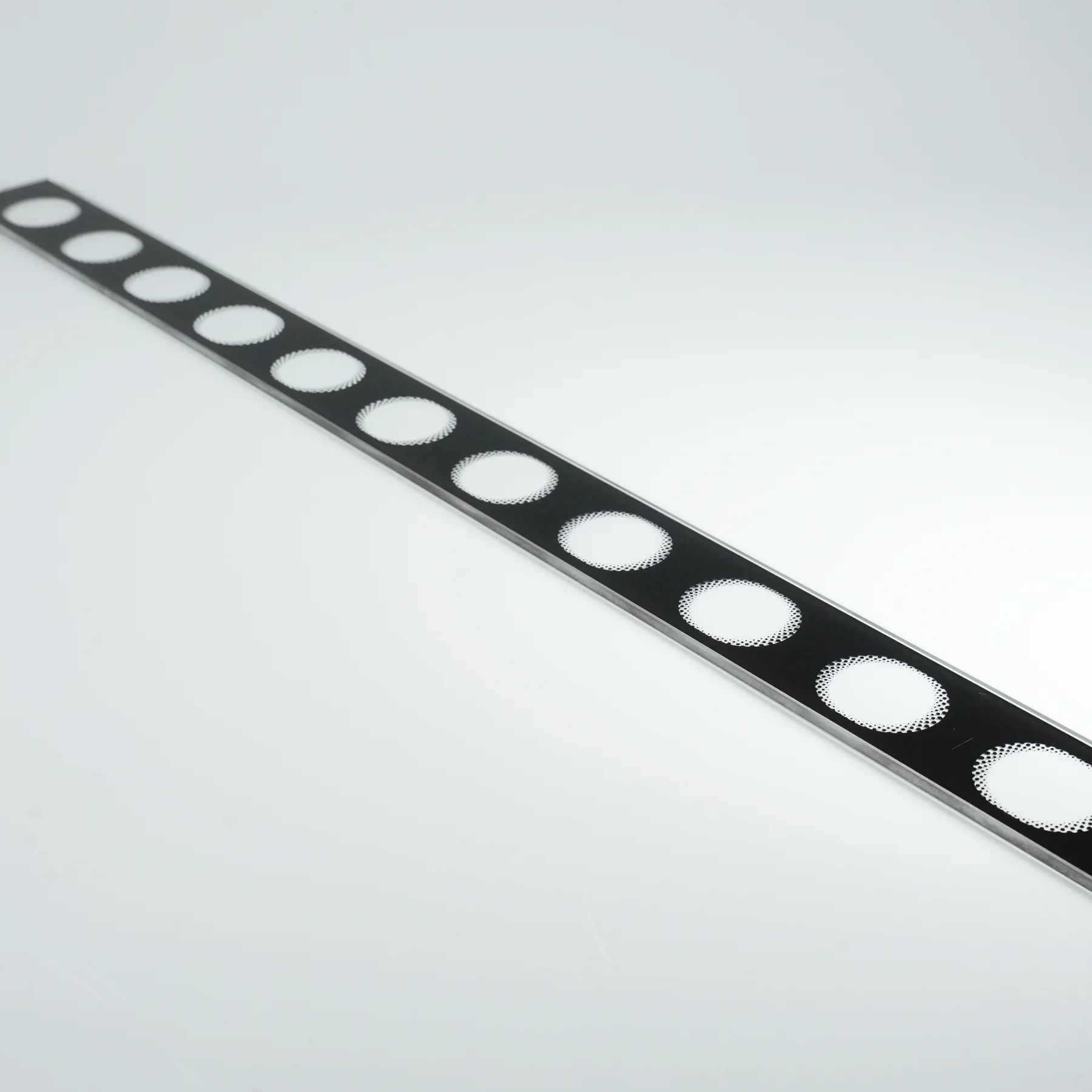 Real printed glass strip showing repeated halftone dot transitions and fine edge detail.