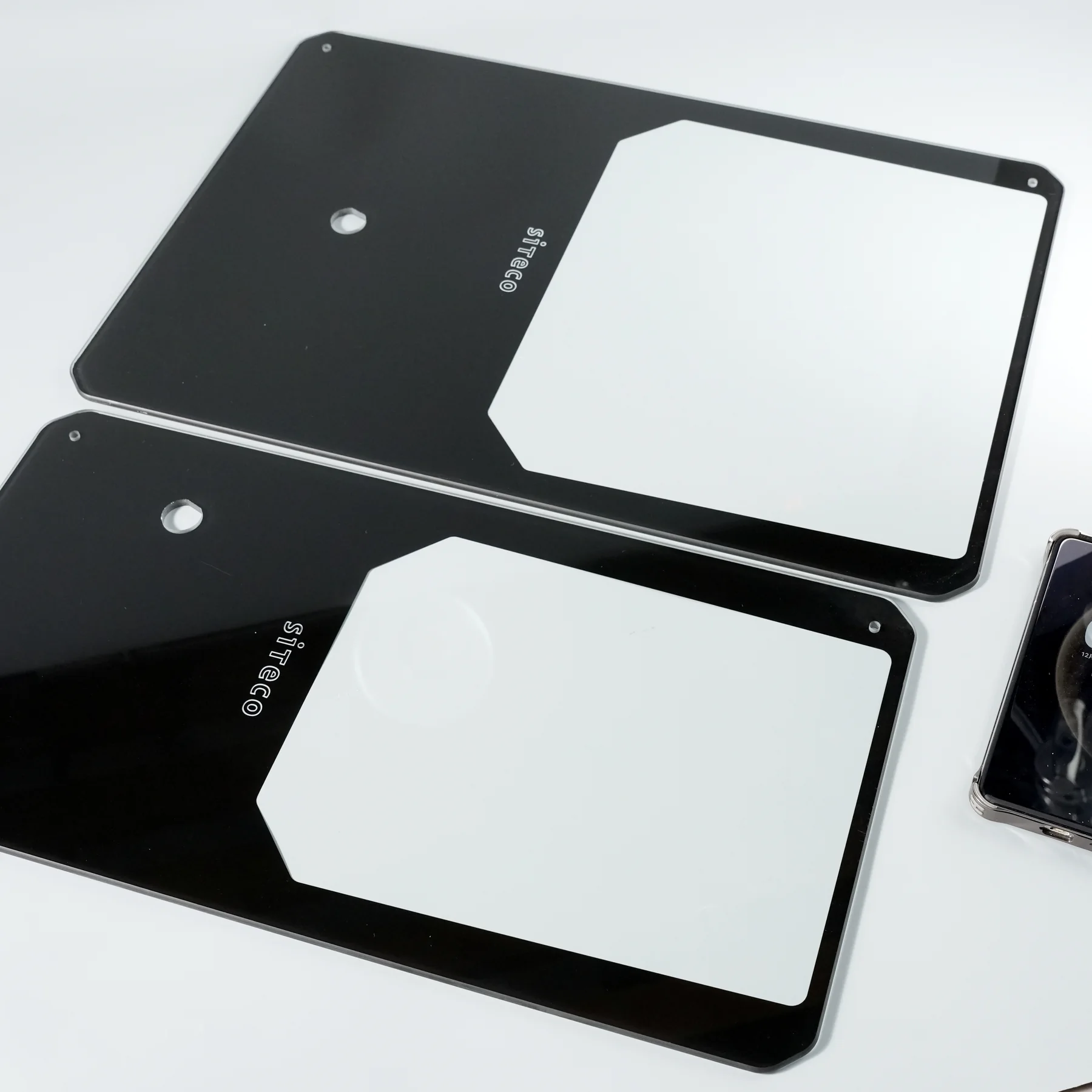Real industrial black cover-glass panels with large windows, machined holes and shaped corners.