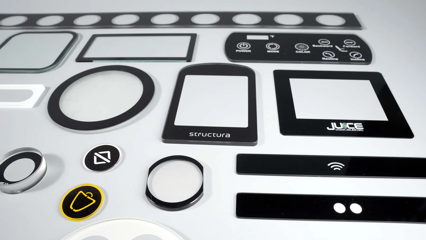 Real screen-printed control-panel and cover-glass samples in multiple geometries.