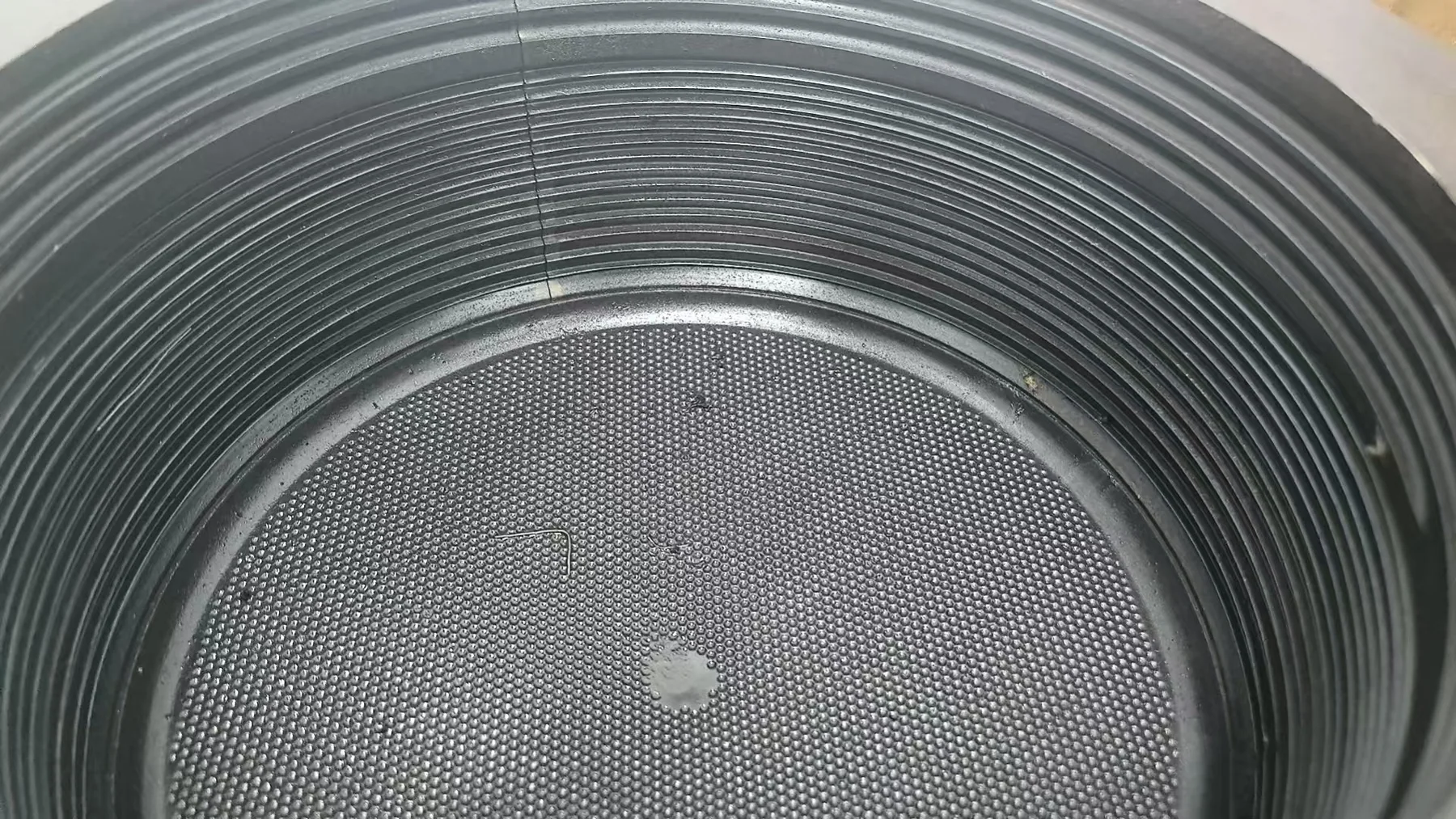 Close view of concentric ribs and a fine repeated texture on a metal mould surface