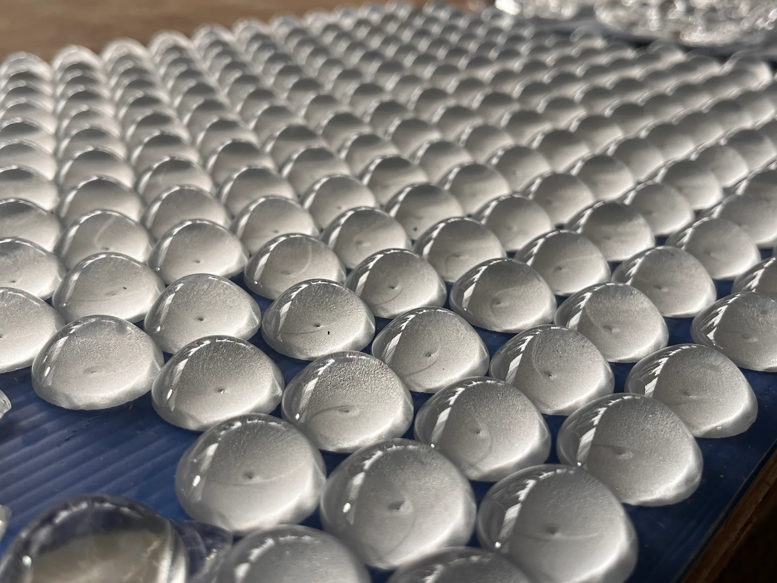 Rows of circular glass pieces with matte-looking curved faces on a work surface