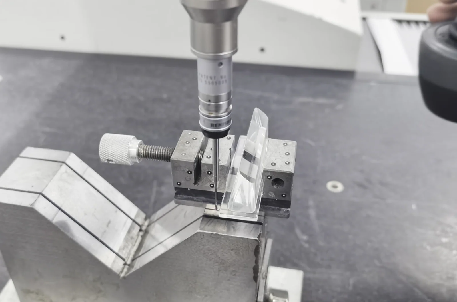 Coordinate measuring probe positioned over a small metal feature in a fixture