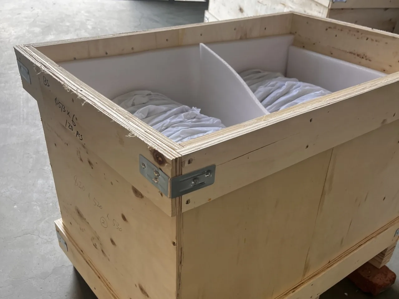 Partitioned wooden crate prepared with protective material for glass components.